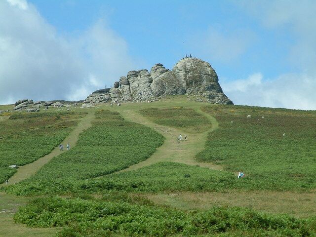 A grassy hill with a rocky outcrop and a winding path.