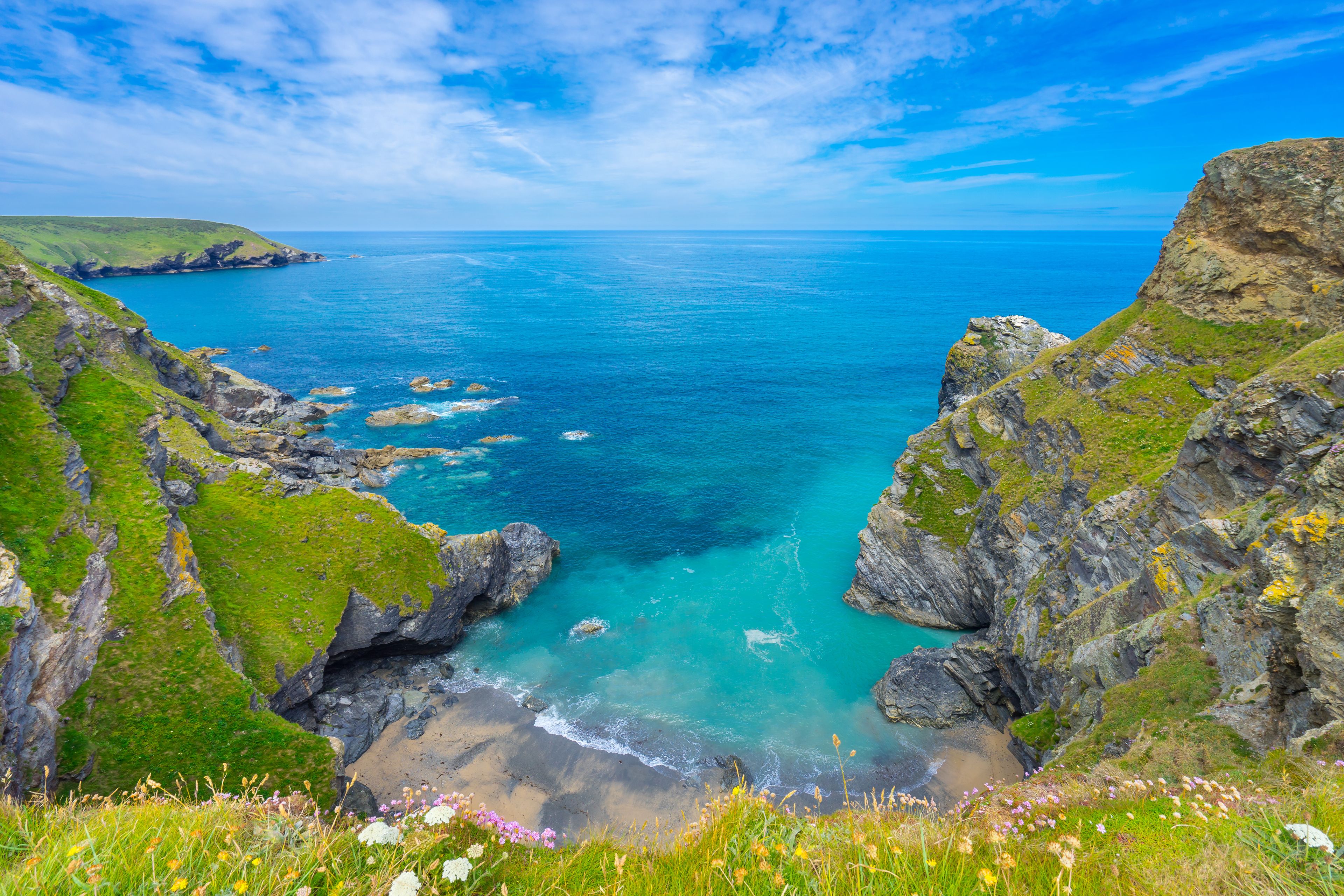 View of the South Devon coast, England, in the summer with clear waters, blue sky and grass.