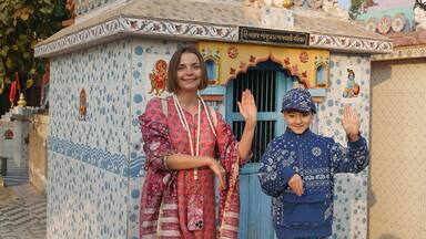 Hindu temple in Bhuj city, Gujarat, India. Indian landmark, beautiful architecture, monument, sight. Tourist woman in pink shalwar kameez, traditional dress with chuld, kid. Hinduism. Building facade