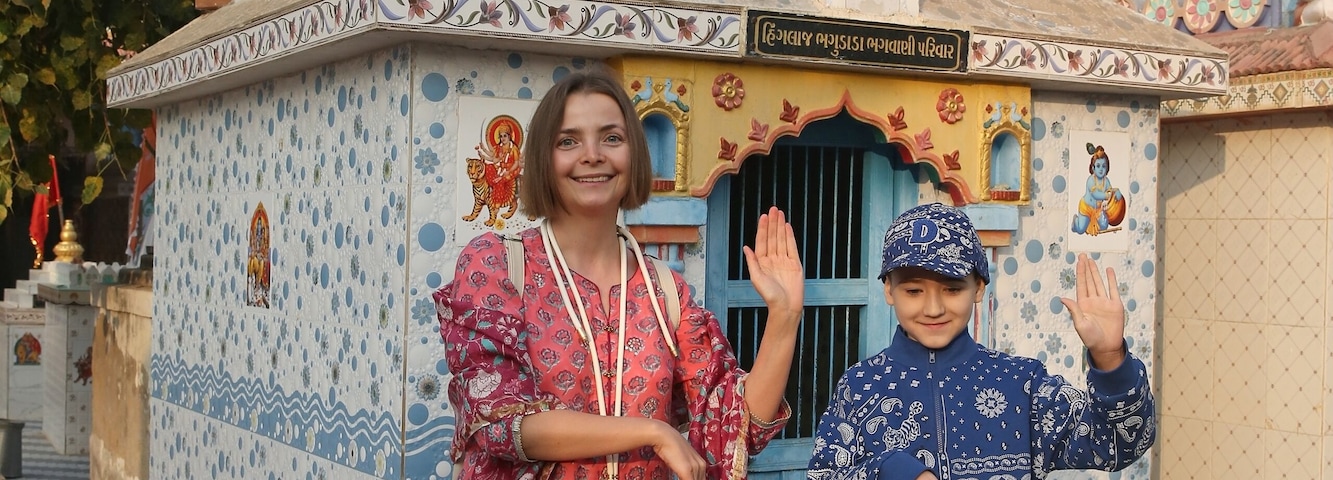Hindu temple in Bhuj city, Gujarat, India. Indian landmark, beautiful architecture, monument, sight. Tourist woman in pink shalwar kameez, traditional dress with chuld, kid. Hinduism. Building facade
