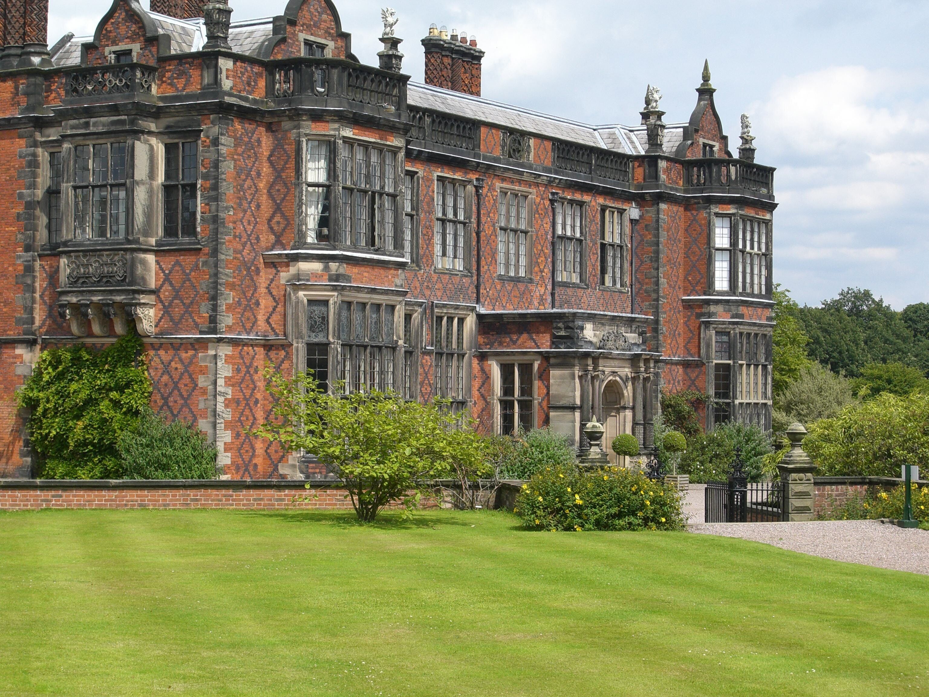 A large, ornate brick building with intricate window designs and a well-maintained lawn.