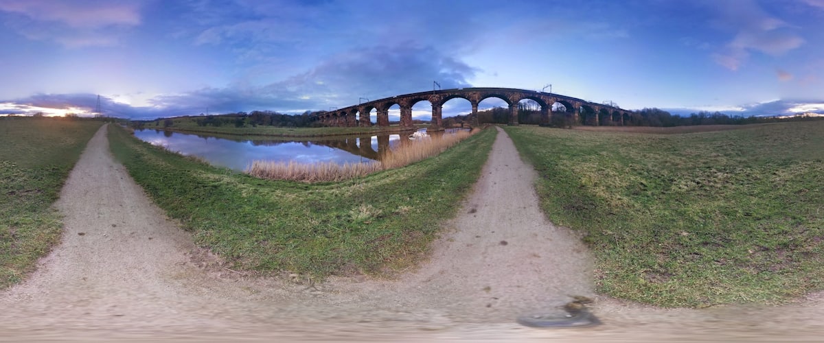 A viaduct over a river with a grassy path leading to it.