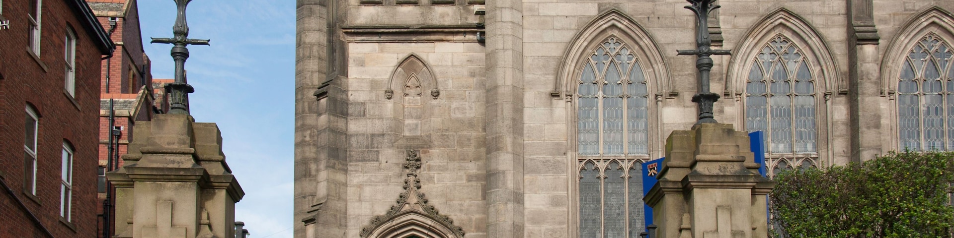Una iglesia histórica con una torre del reloj, una puerta verde y ventanas góticas.