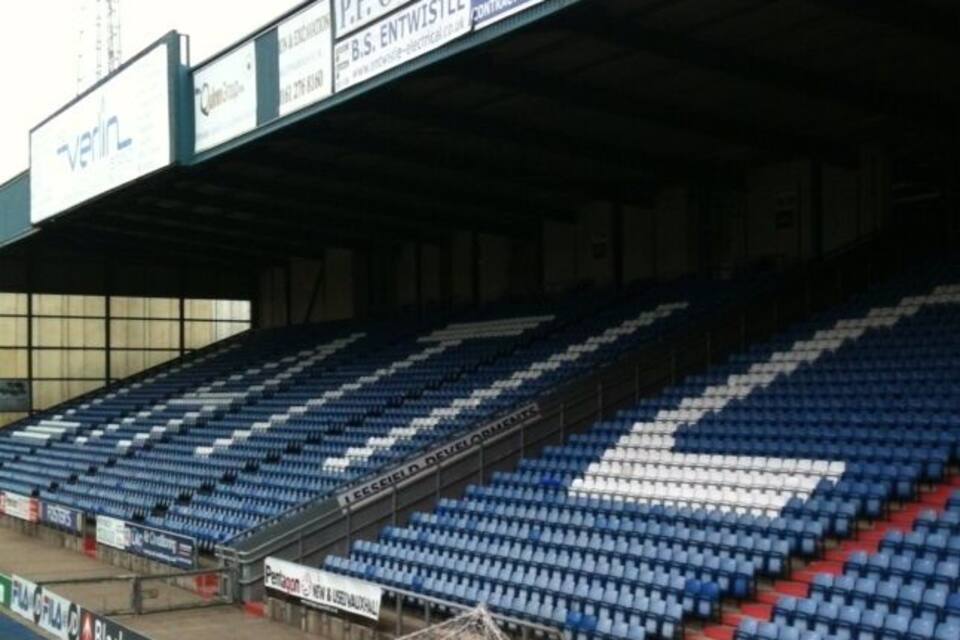 A stadium with blue seats, advertisements, and a goalpost.