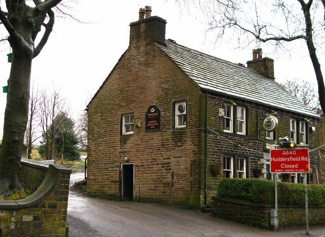 A brick building with a sign indicating 'Huddersfield Rd. Closed when lights flash'.