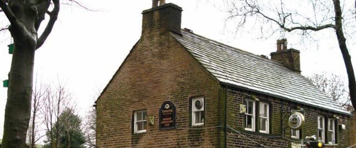 A brick building with a sign indicating 'Huddersfield Rd. Closed when lights flash'.