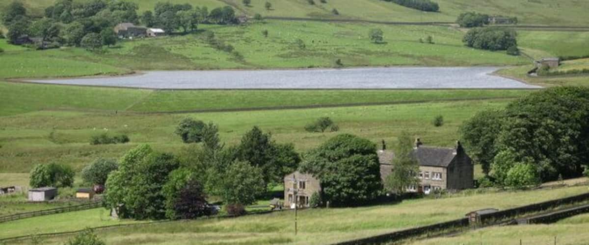 Un paysage rural caractérisé par des collines douces, un lac et des maisons dispersées.