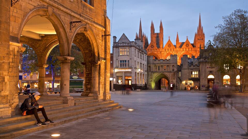 A historic square with medieval architecture, including a prominent church with spires and a Starbucks.