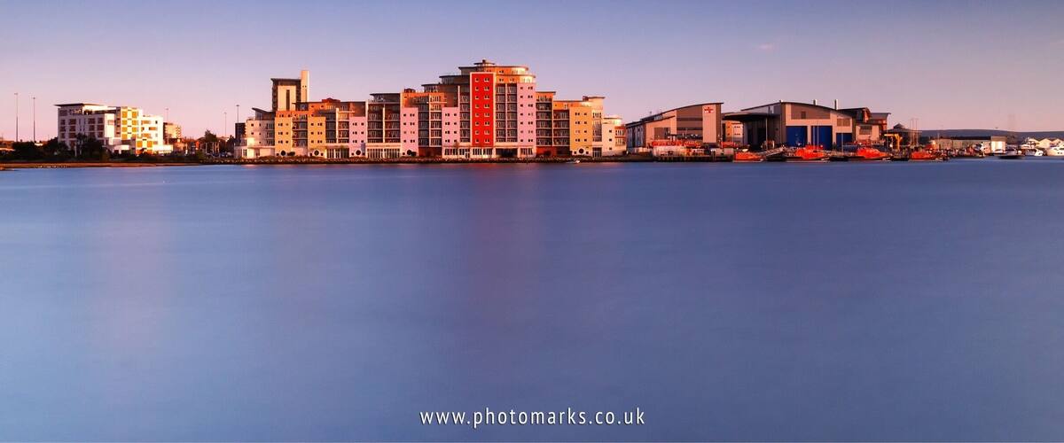 Aqua Lifeboat Quay and the RNLI training college viewed at dusk from across Holes Bay, Poole, Dorset.