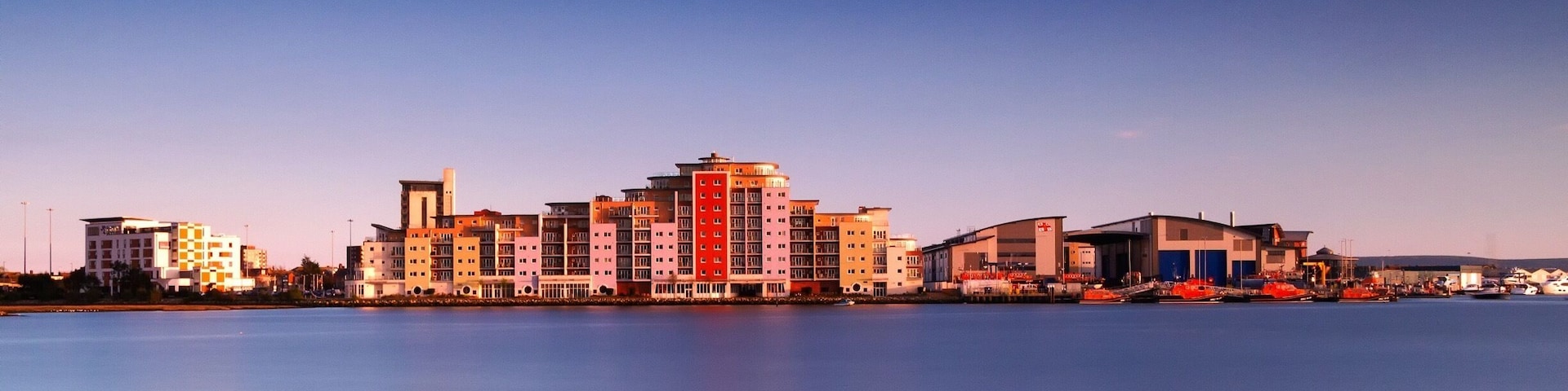Aqua Lifeboat Quay and the RNLI training college viewed at dusk from across Holes Bay, Poole, Dorset.