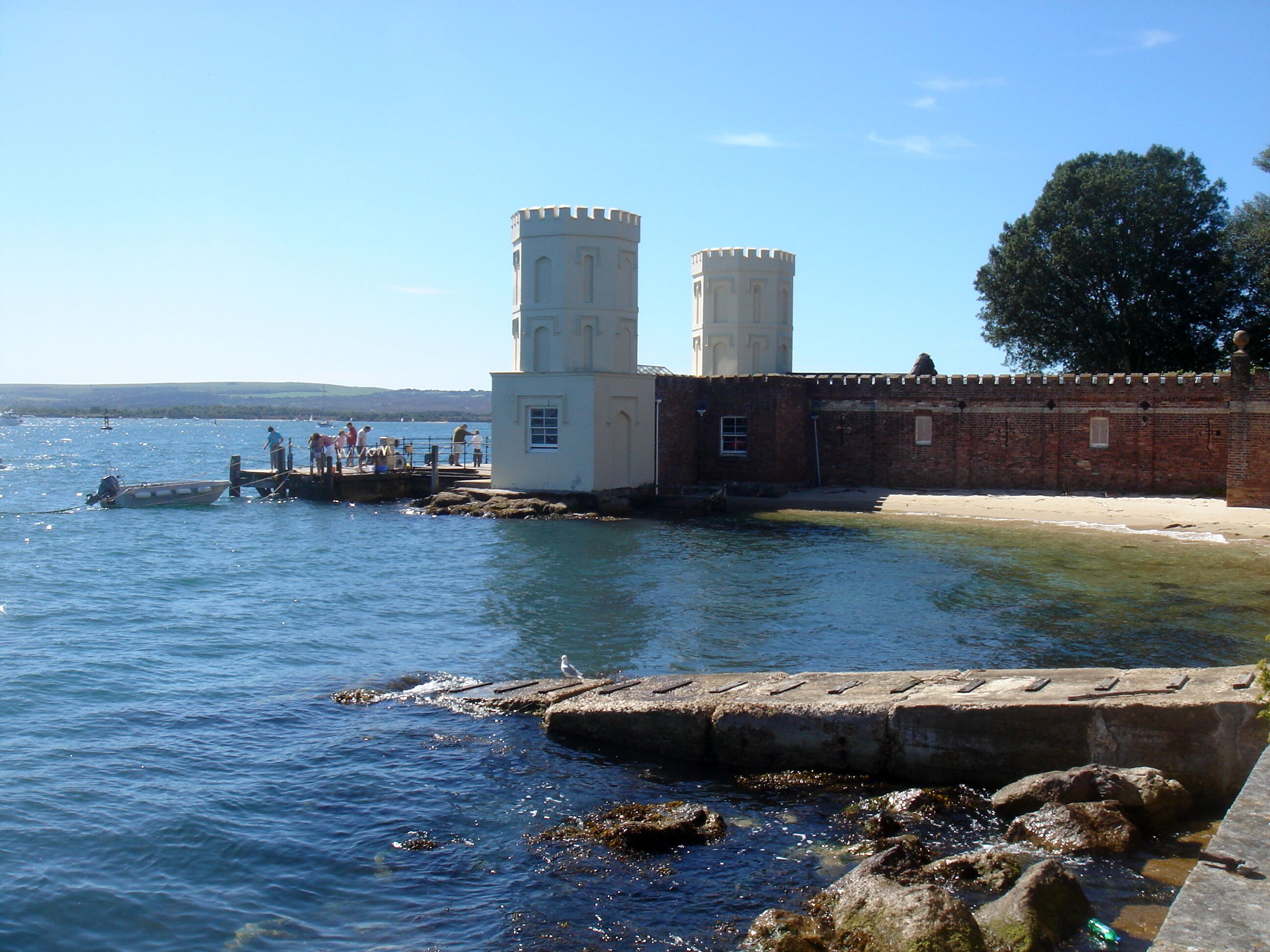 A coastal fort with two towers, a sandy beach, and calm waters.