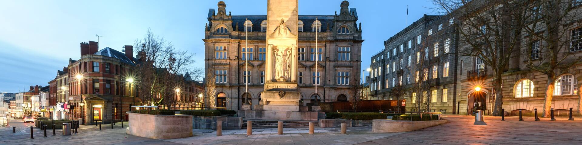 A historic building with a prominent central tower and a statue base in the foreground.