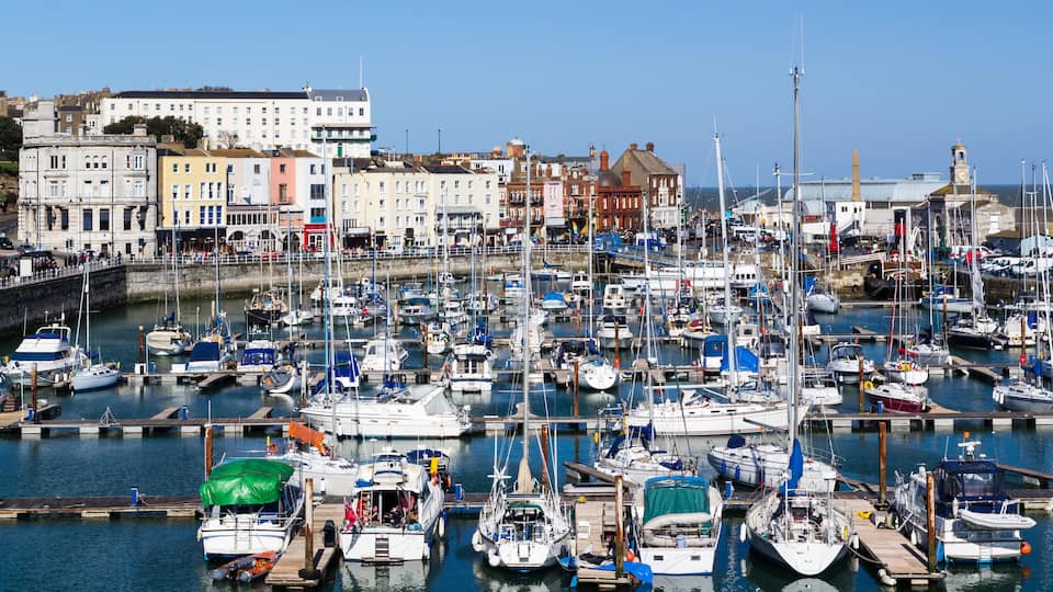 A marina filled with boats, a clock tower, and historic buildings in the background.