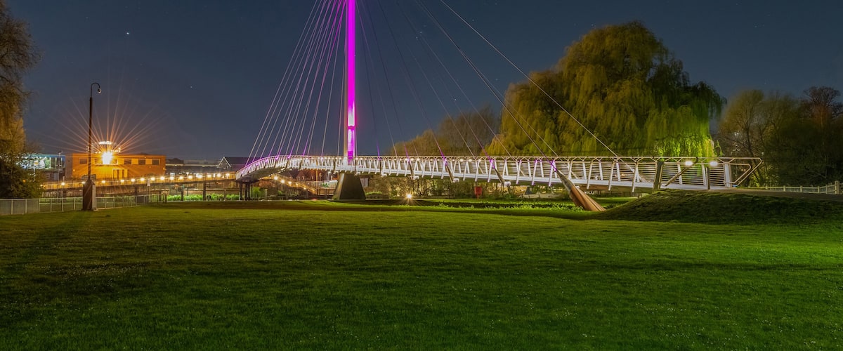 Un pont doté d’une haute tour centrale, d’un croissant de lune et d’un parc avec de l’herbe et des arbres.