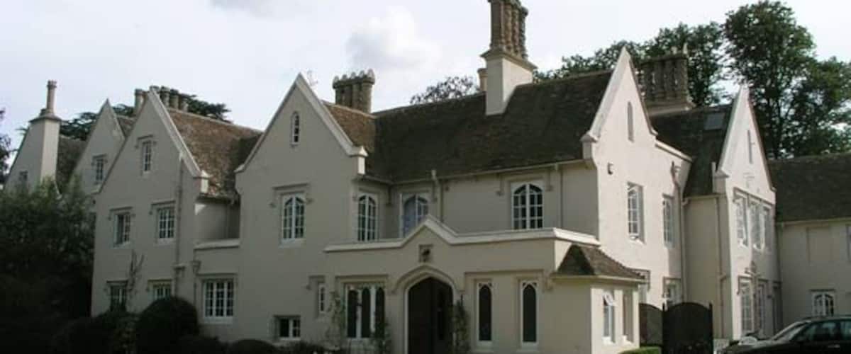 A large, stately building with multiple chimneys, a prominent entrance, and a well-maintained lawn.