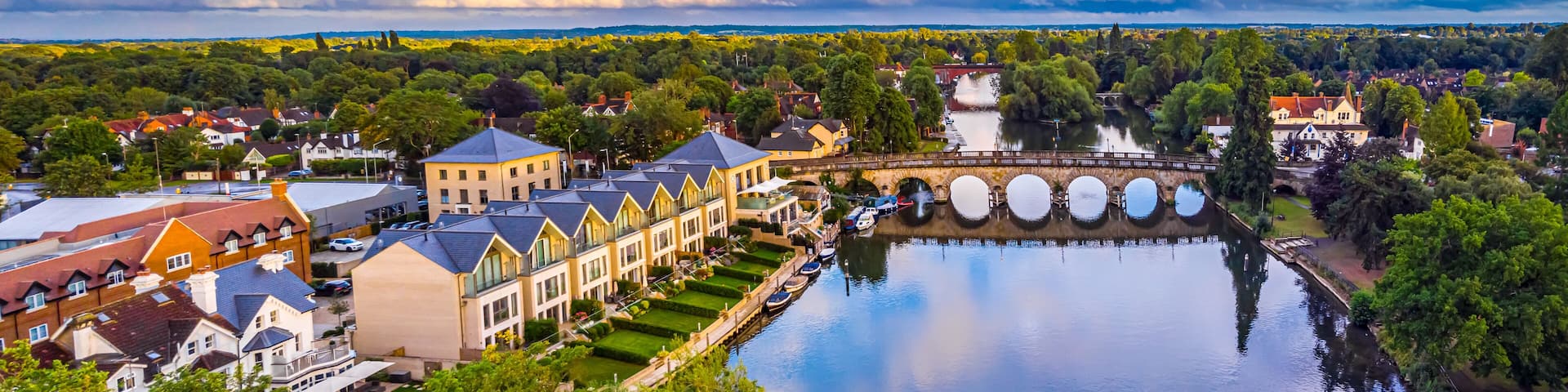A riverside town with a bridge, a row of houses, and a large body of water.
