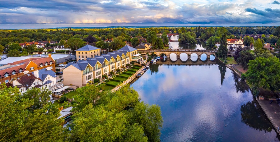 A riverside town with a bridge, a row of houses, and a large body of water.