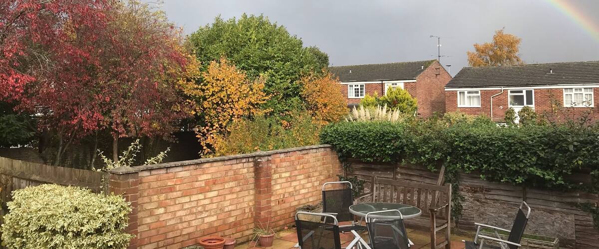 A garden with a brick wall, potted plants, and a table with chairs.