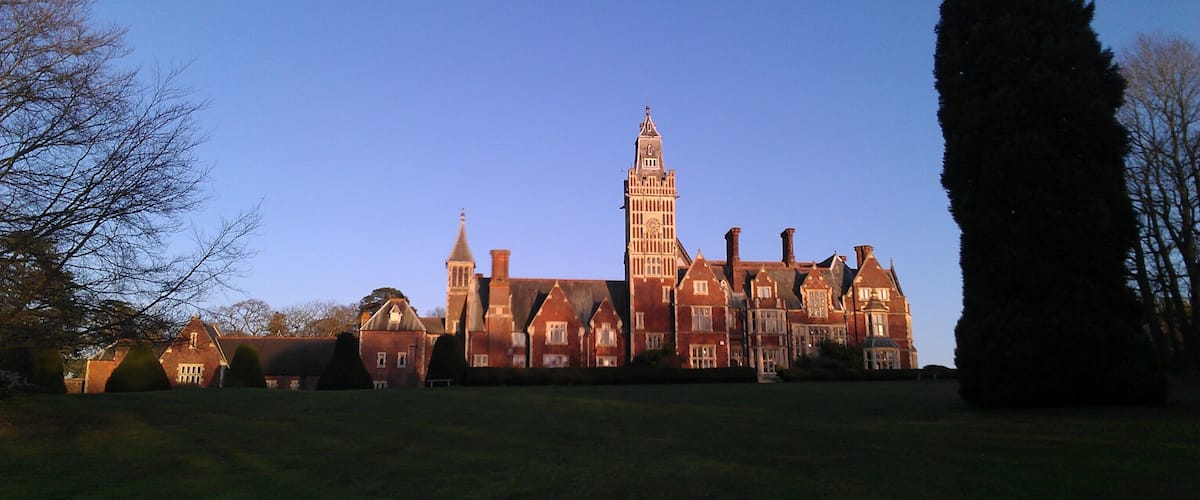 A large, historic building with a prominent tower and multiple chimneys.