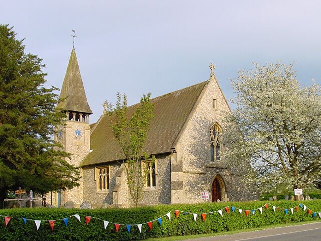A church with a tall steeple and a clock tower, surrounded by blooming trees and a string of flags.