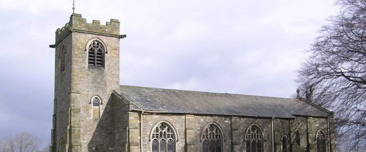 Una iglesia histórica con una torre alta y ventanas de arco.