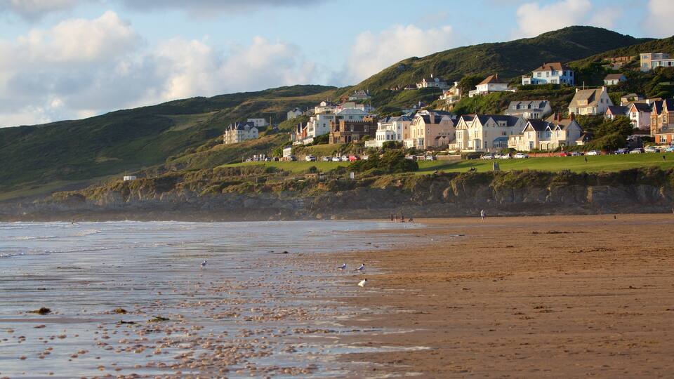 A coastal town with houses on a hillside, a sandy beach, and the sea.