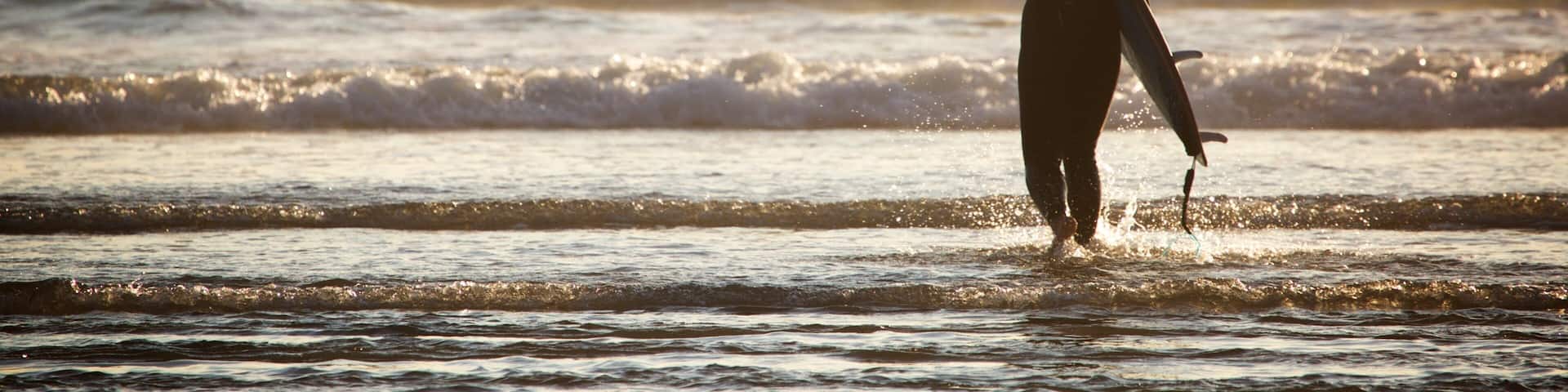 A surfer standing in the ocean with waves crashing around them.