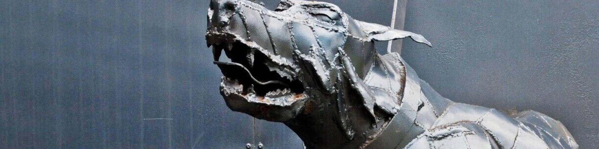 A metallic sculpture of a running animal, possibly a horse, mounted on a wall.