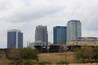 A city skyline with tall buildings, including a Wells Fargo skyscraper, and a train track with a train in the foreground.