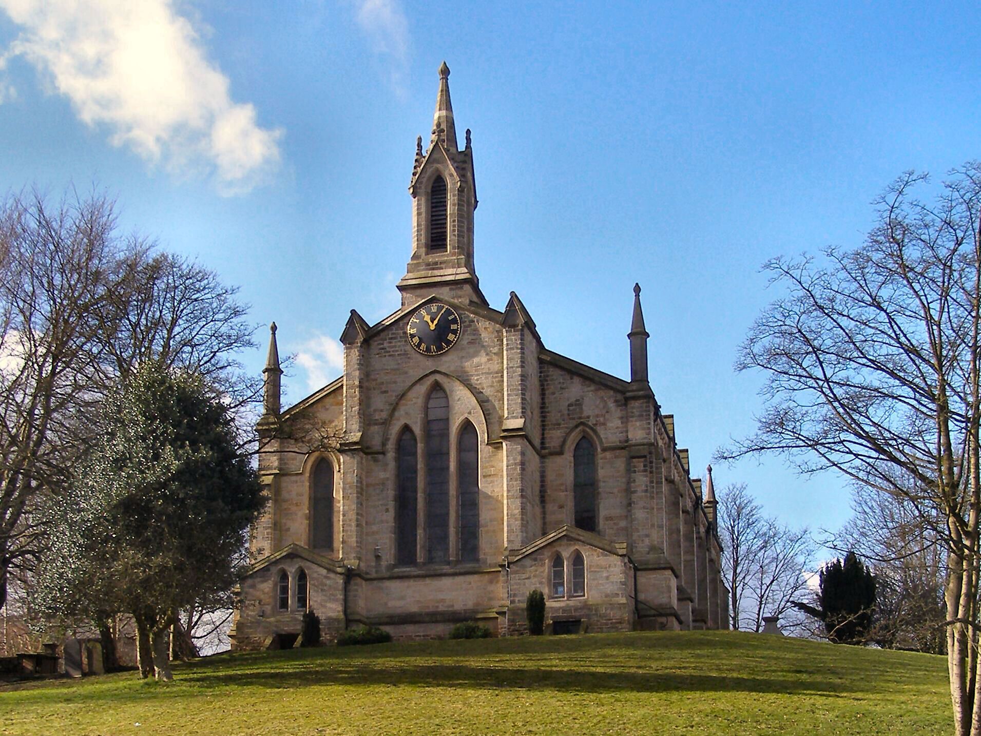 A large stone church with a tall steeple and a clock on the front.