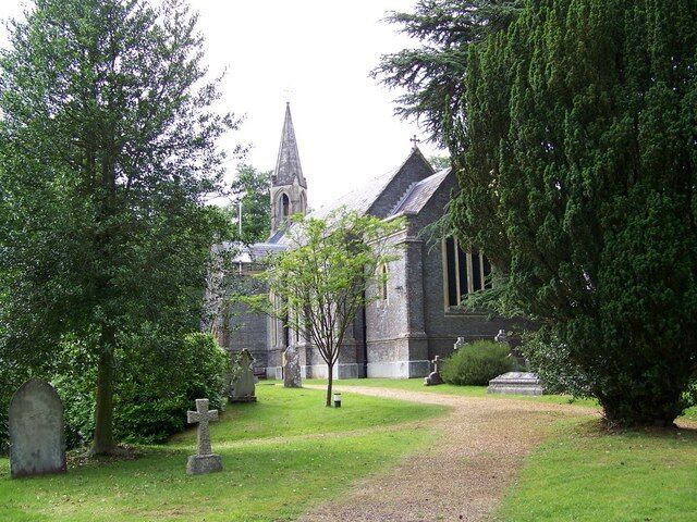 A church with a tall steeple, surrounded by trees and gravestones.