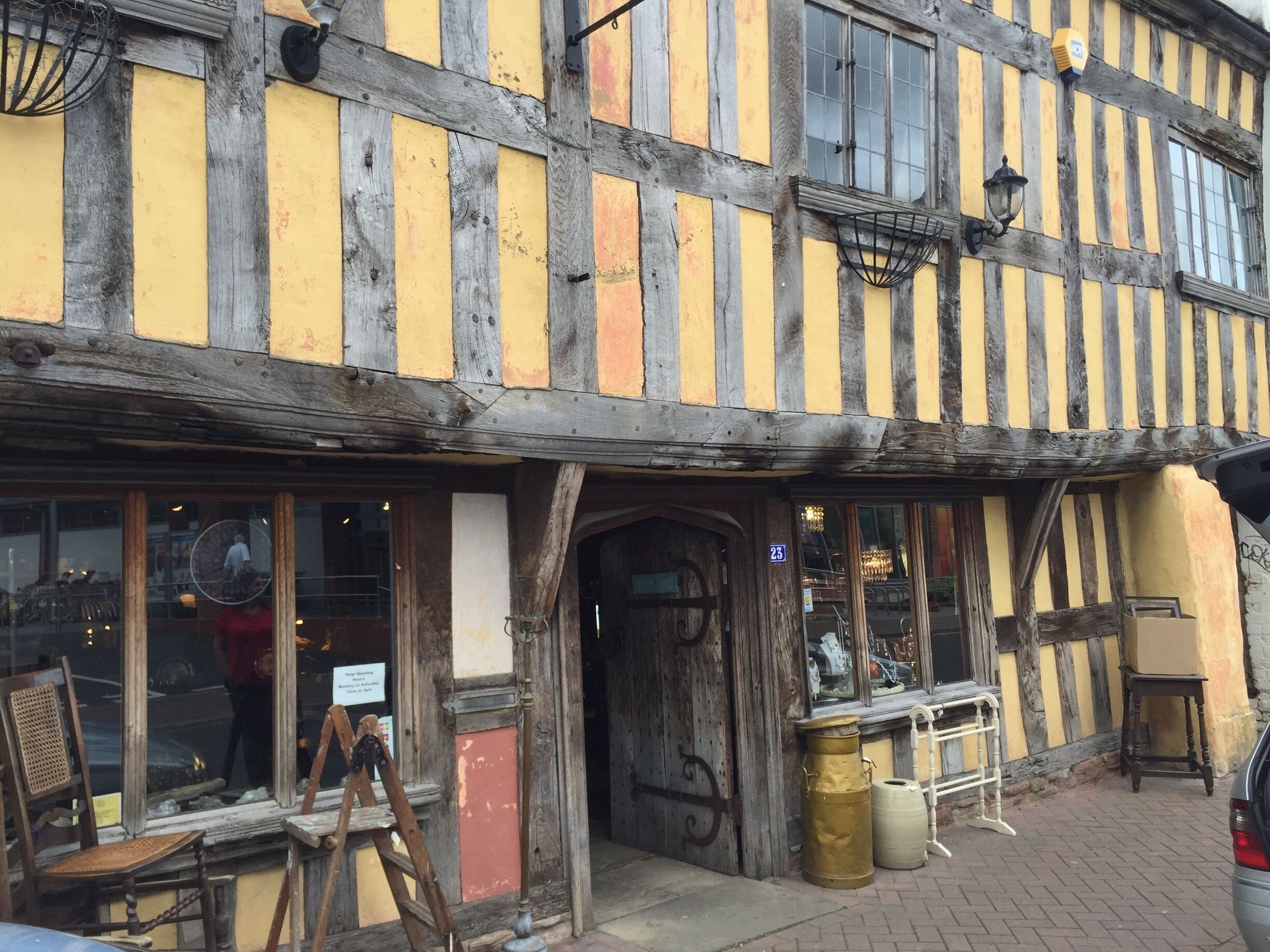 A half-timbered building with a yellow and black facade, a wooden door, and a sign indicating it is a restaurant.