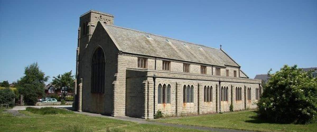 A stone church with a large arched window and a bell tower.
