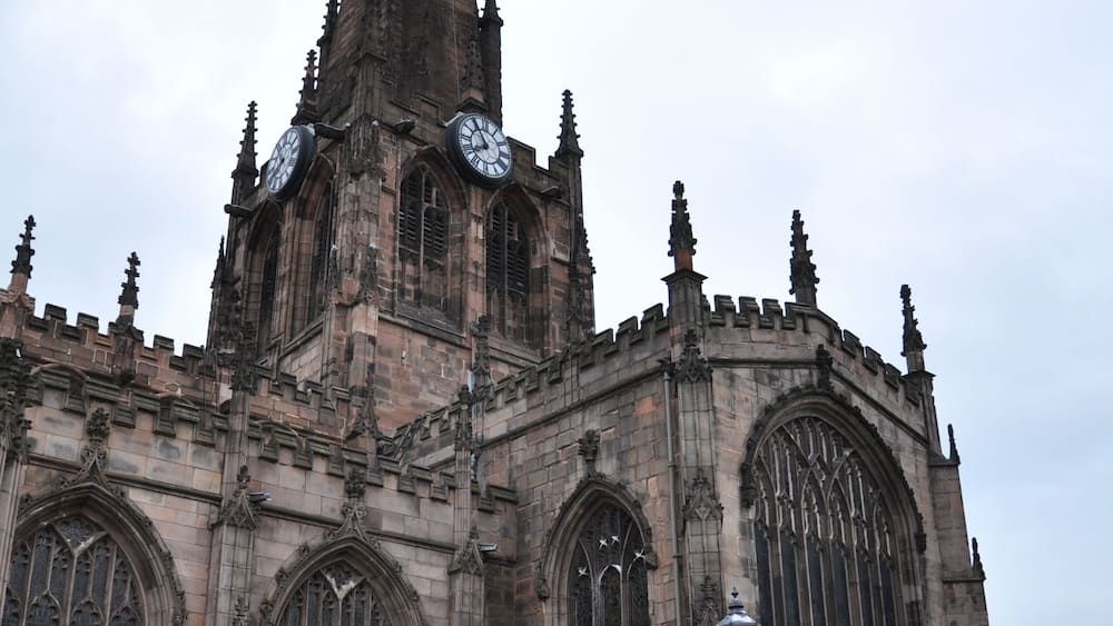 A historic church with a tall spire, large arched windows, and a clock tower.