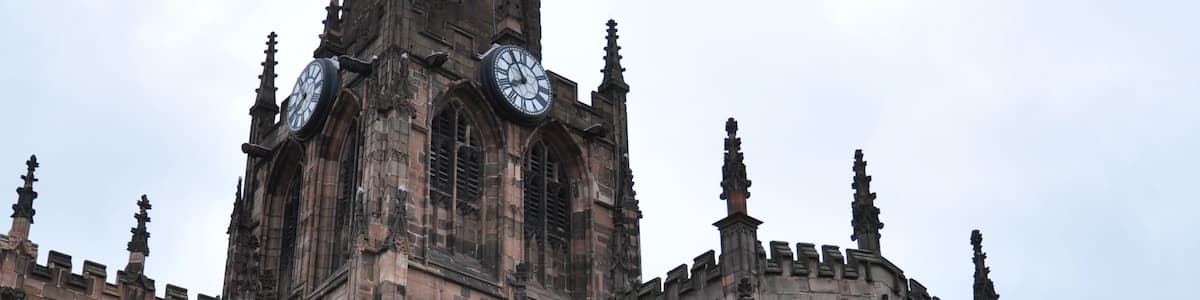 Eine historische Kirche mit einem hohen Turm, großen Rundbogenfenstern und einem Glockenturm.