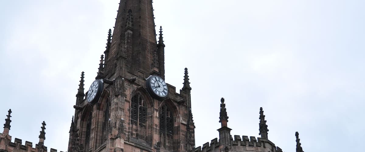 A historic church with a tall spire, large arched windows, and a clock tower.
