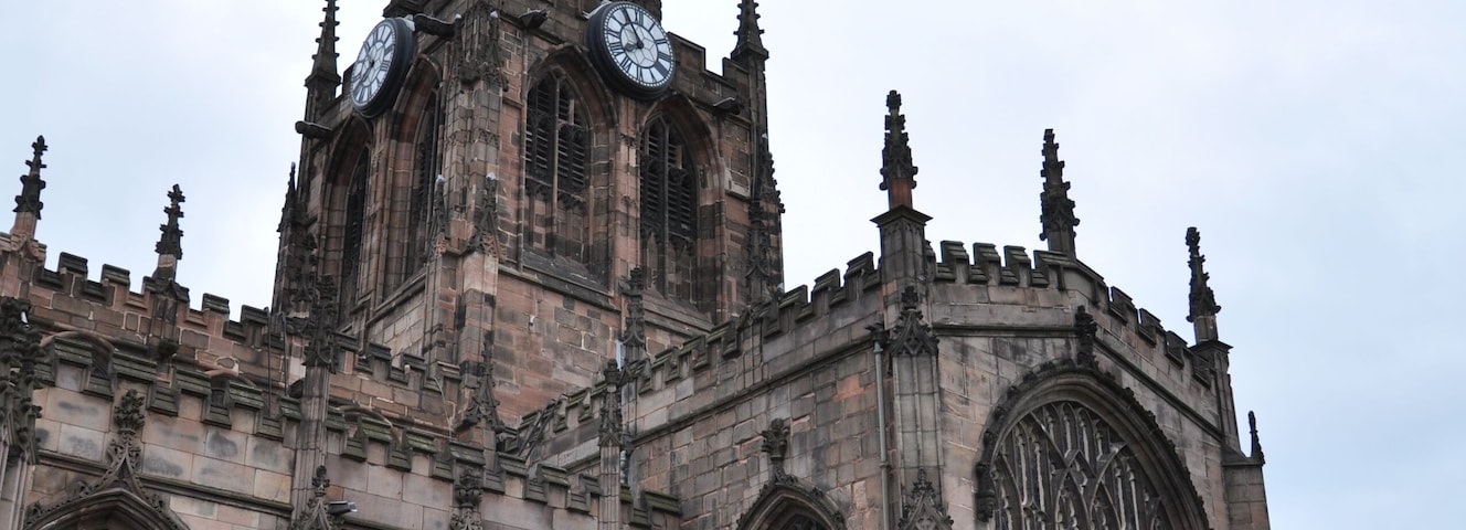 A historic church with a tall spire, large arched windows, and a clock tower.