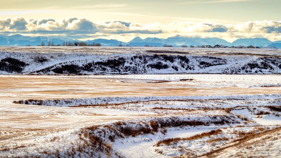 A snow-covered landscape with rolling hills and distant mountains.