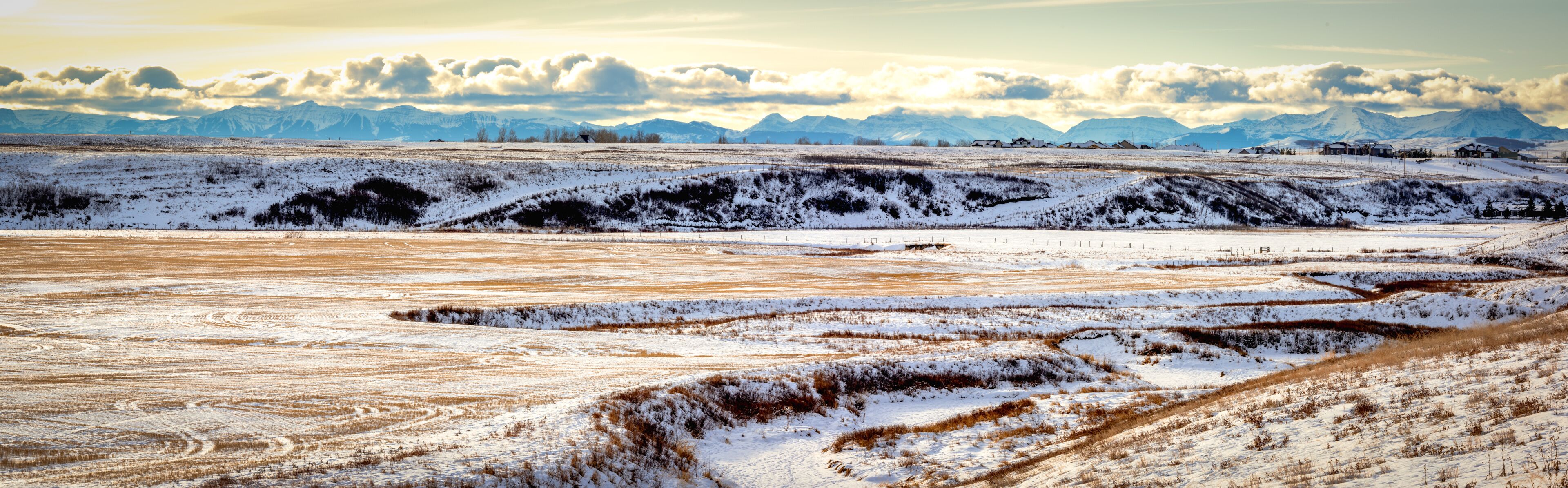 A snow-covered landscape with rolling hills and distant mountains.