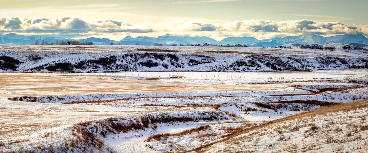A snow-covered landscape with rolling hills and distant mountains.