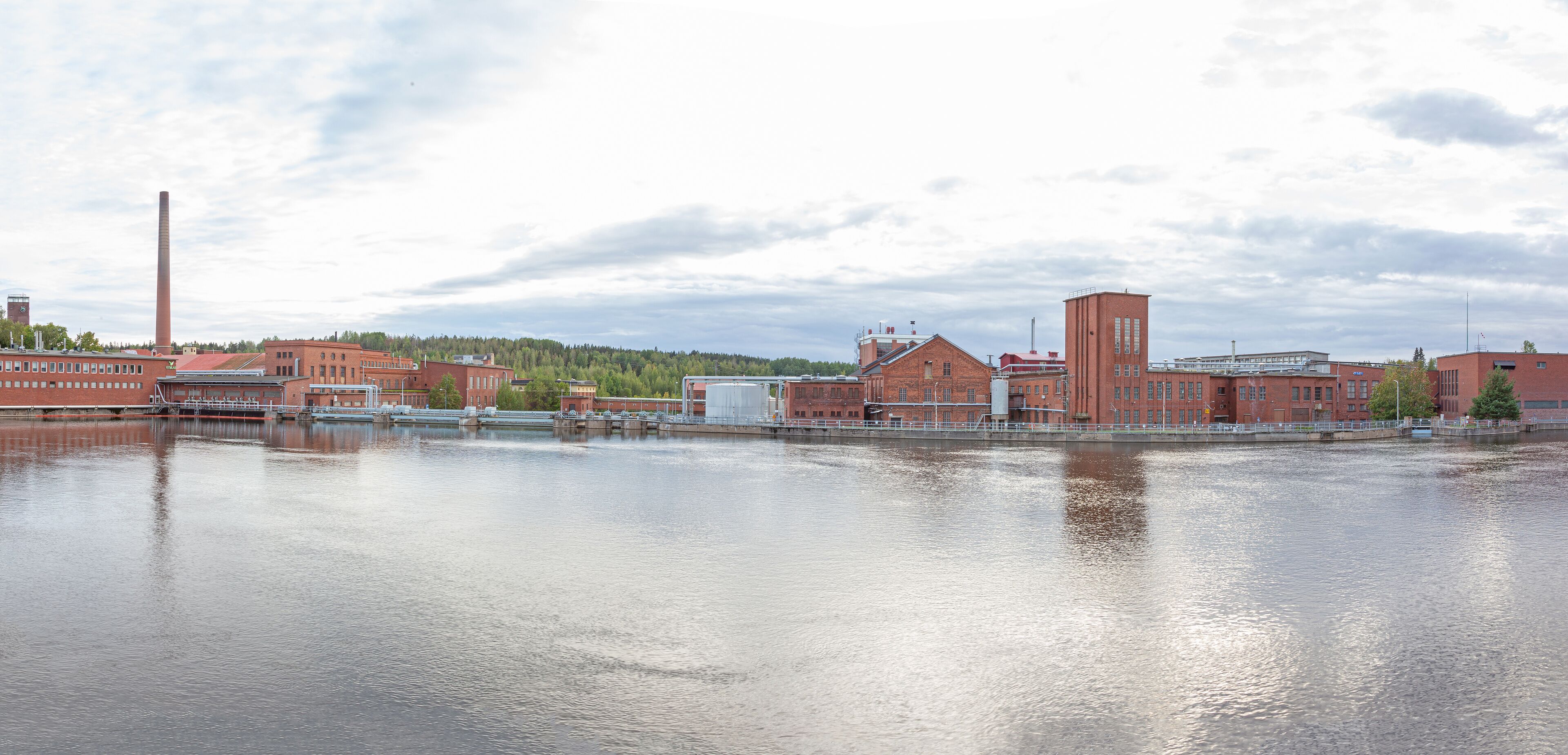 A river with industrial buildings and a tall chimney.