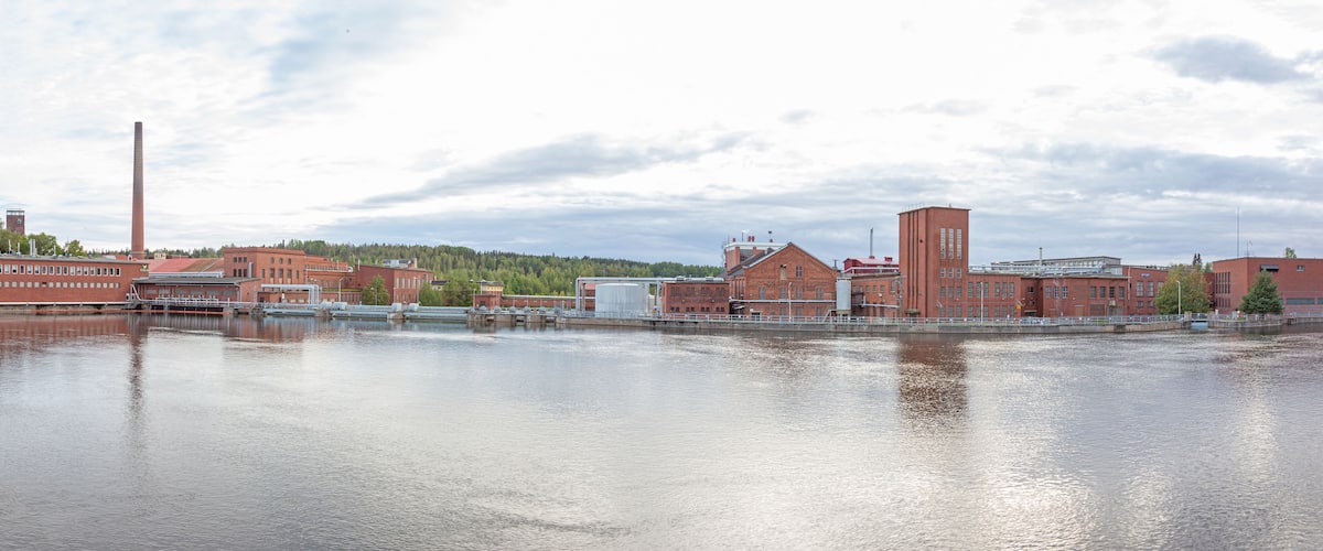 A river with industrial buildings and a tall chimney.