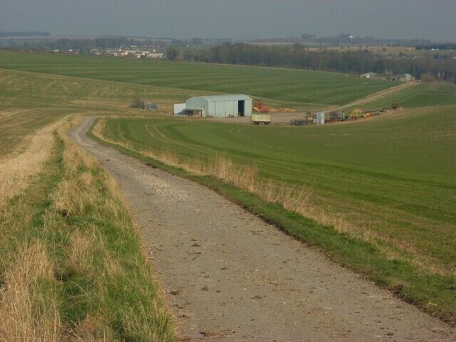 Farm road above Shrewton Between large arable fields as it drops down to Barleycroft Farm, the second group of buildings (far right).