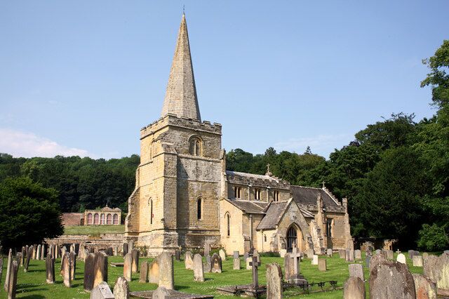 A church with a tall spire and a graveyard.