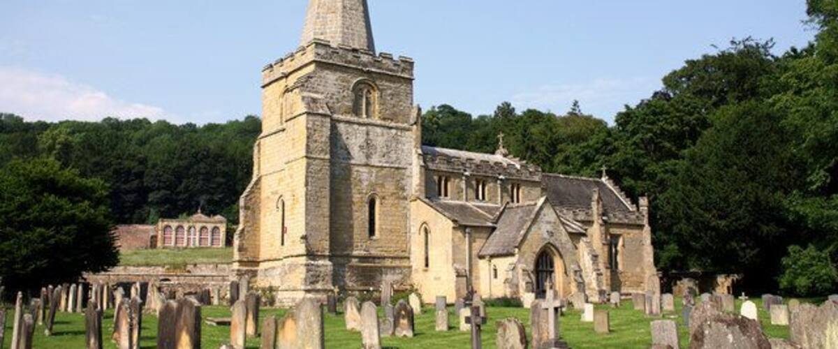 A church with a tall spire and a graveyard.