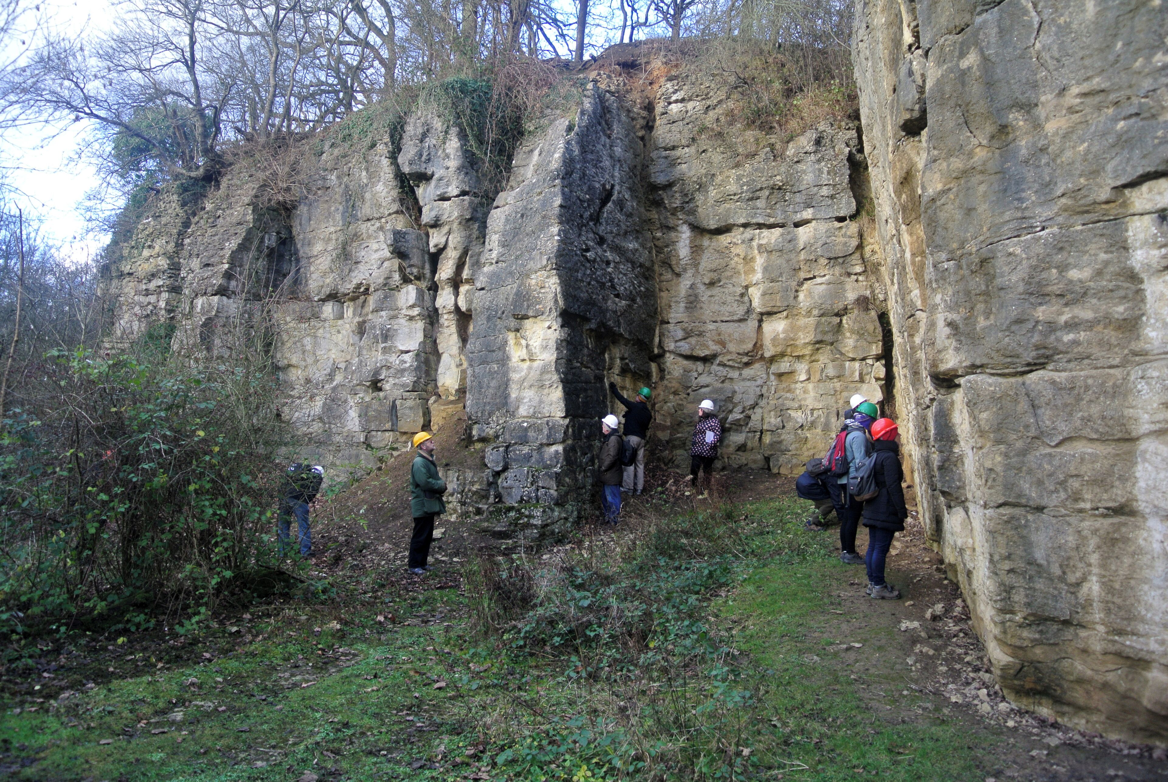 A group of people hiking on a rocky trail surrounded by cliffs and vegetation.