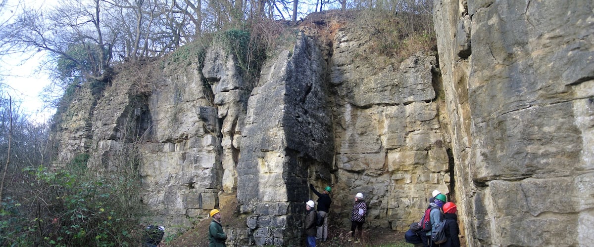 A group of people hiking on a rocky trail surrounded by cliffs and vegetation.