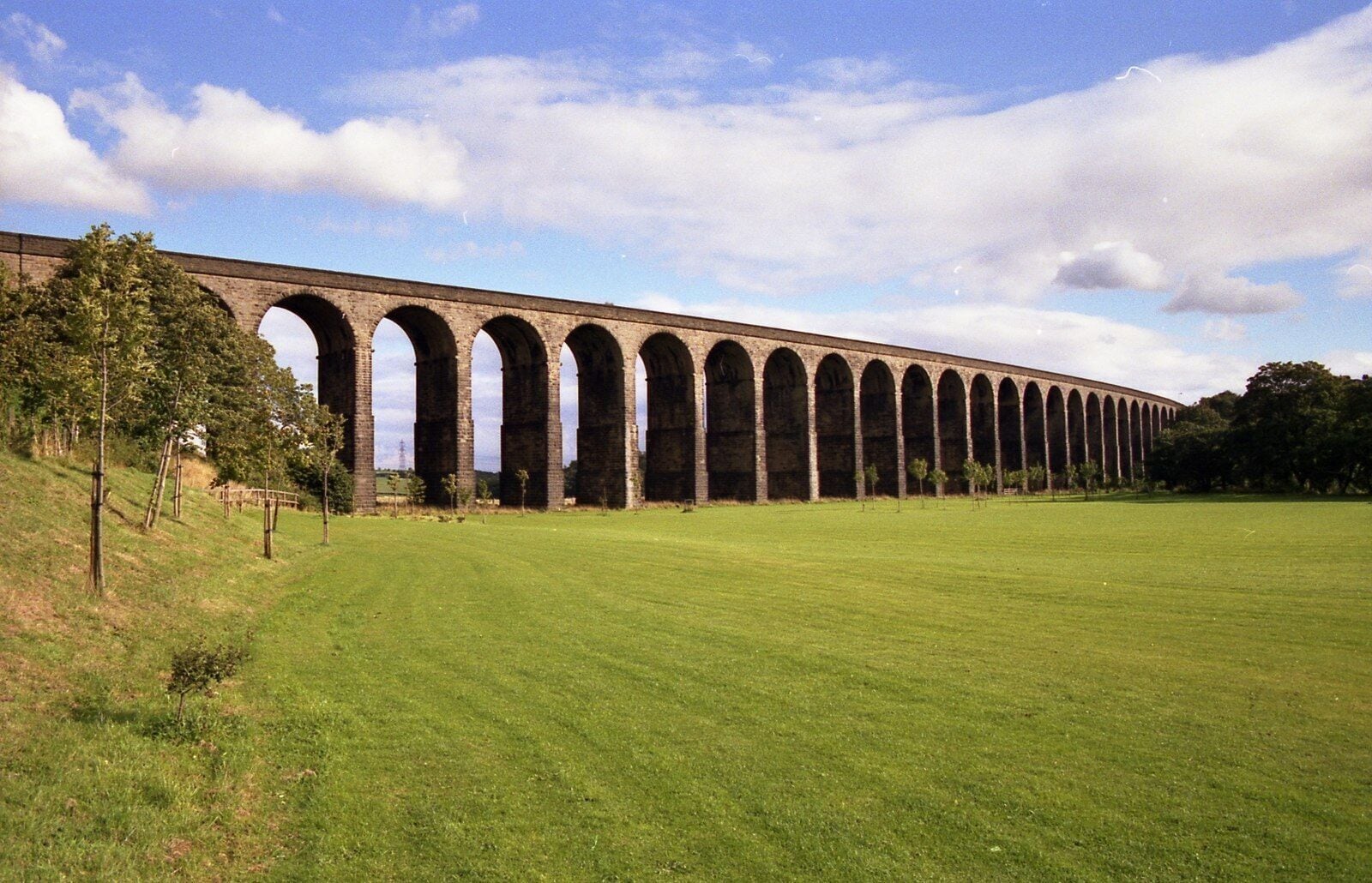 A long viaduct with multiple arches over a grassy field.
