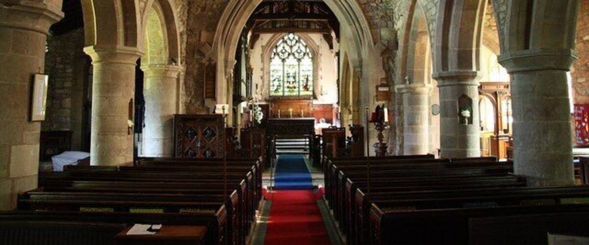 An interior of a stone church with arched ceilings and a central aisle leading to an altar.