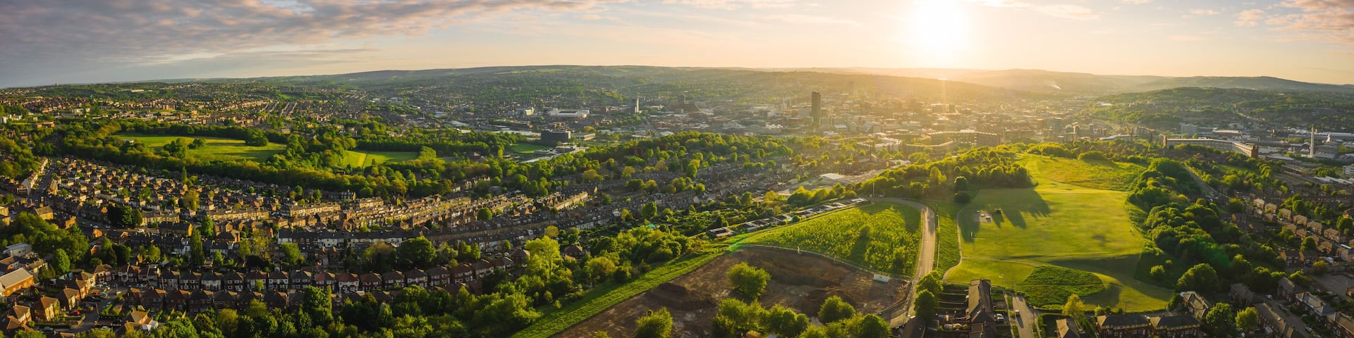 A panoramic view of a city with a river, green parks, and residential areas.